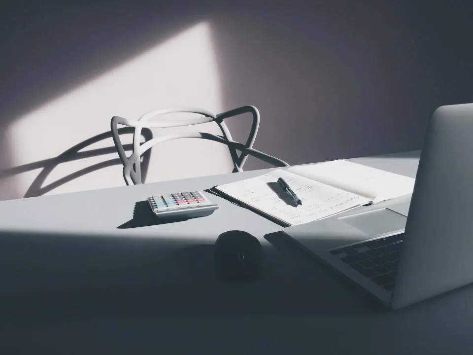 Calculadora, cuaderno y portátil sobre un escritorio