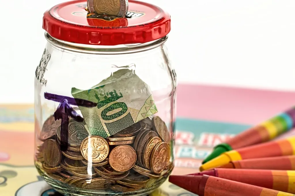Bote de cristal con monedas y un billete guardados