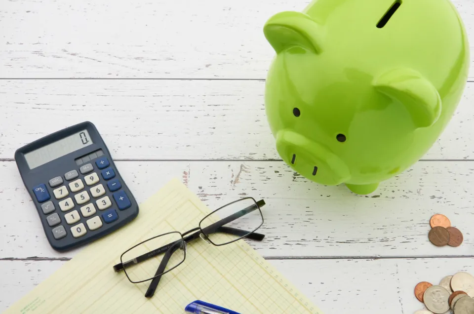 Hucha, calculadora y monedas sobre una mesa